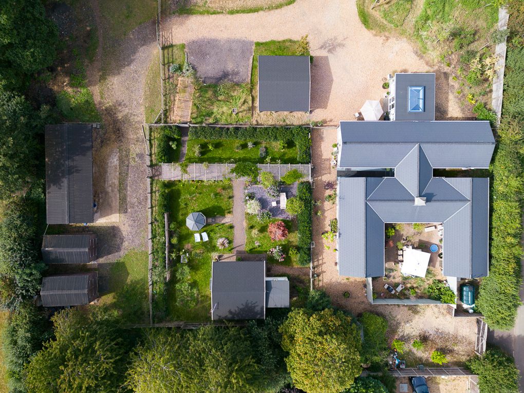 Aerial drone view looking down at suburban homes with green landscaping and pitched roofs. Shot for an estate agent in Stevenage.