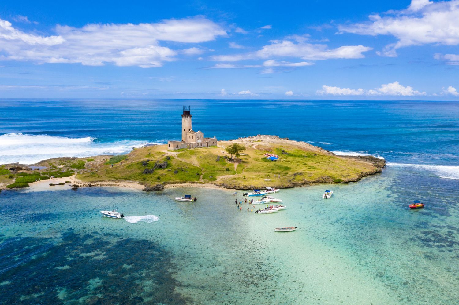 Aerial drone photograph of a tropical island in Mauritius featuring a lighthouse, white sandy beaches and crystal-clear turquoise waters.