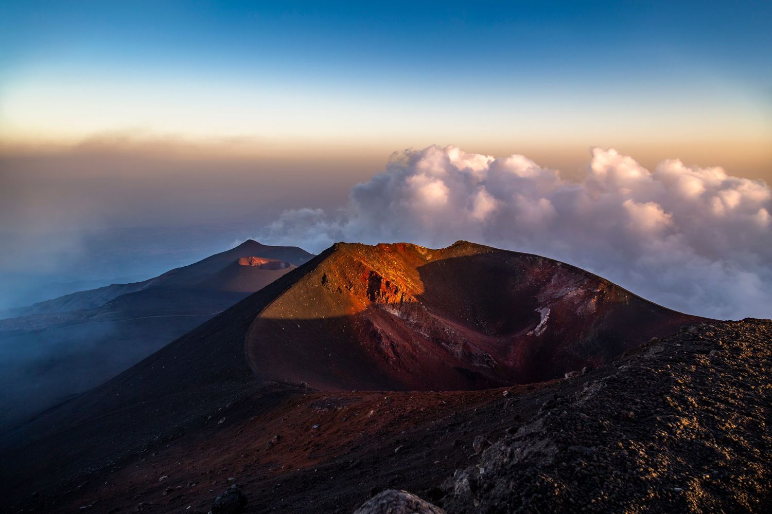 Volcanic crater at sunrise above the clouds on Mount Etna, Sicily, Italy.
