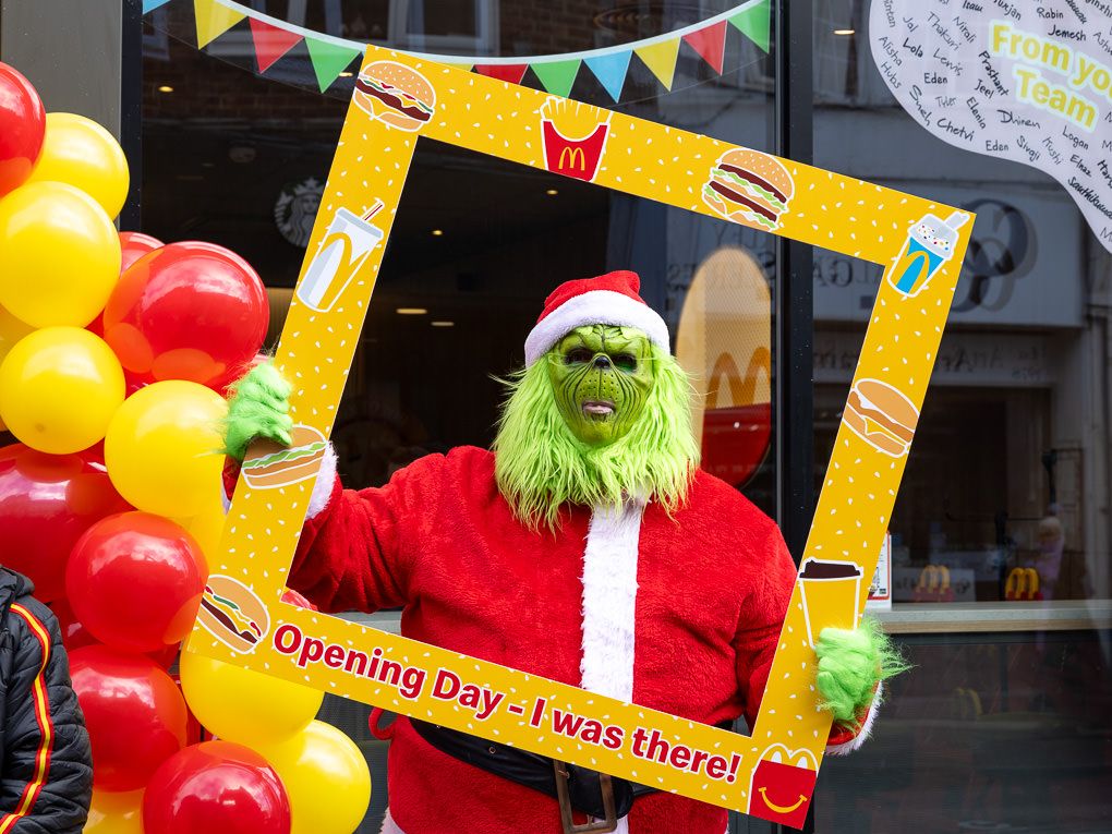 The Grinch mascot outside McDonald’s at the Rickmansworth restaurant opening, photographed for PR use with balloons and festive bunting.