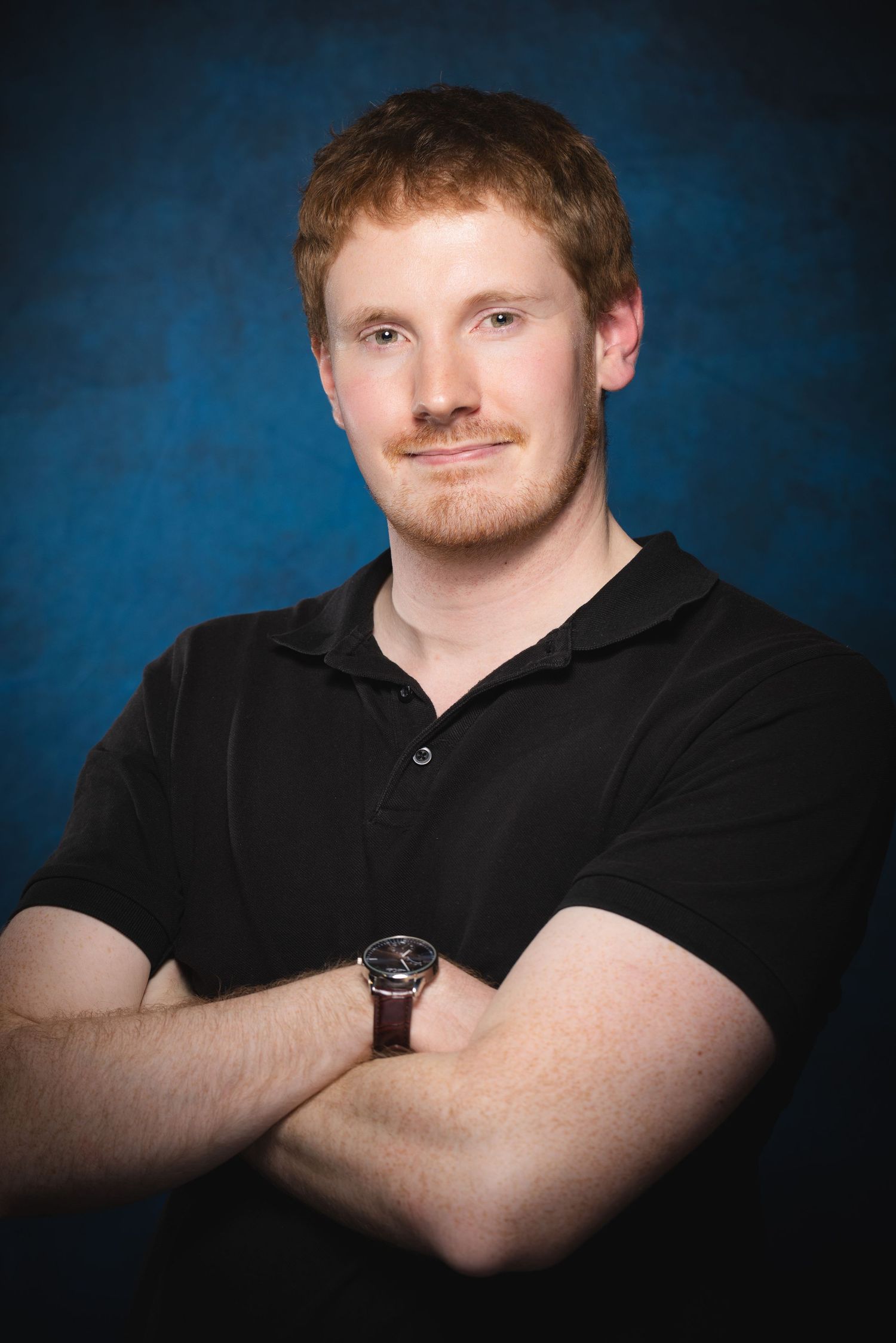 Professional actor headshot with confident pose photographed against blue studio backdrop at Castle Theatre Wellingborough