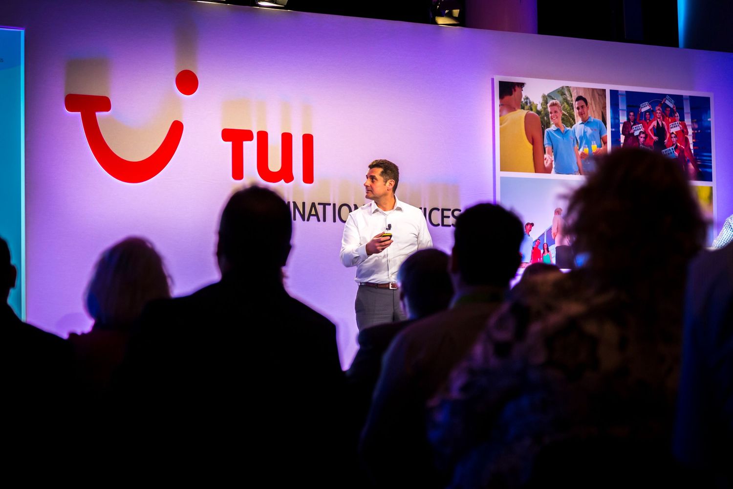 Presenter speaking to delegates in front of a TUI branded screen at a corporate conference event