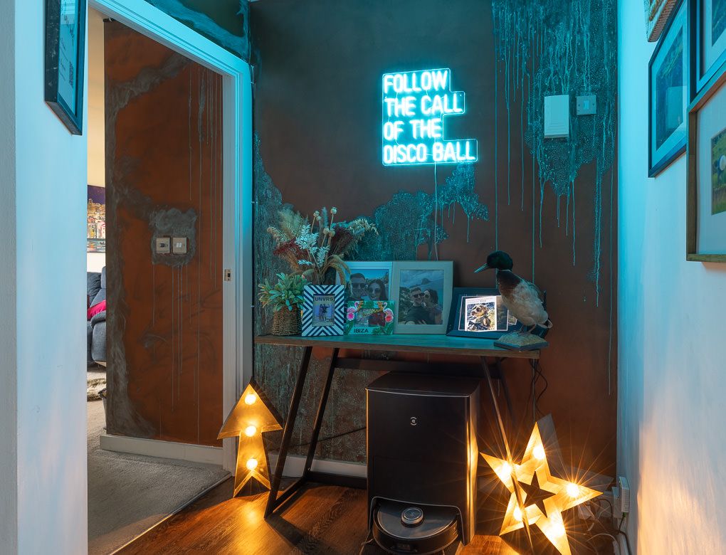 Real estate photography of a hallway with warm lighting, featuring illuminated star decorations and neon blue wall signs.