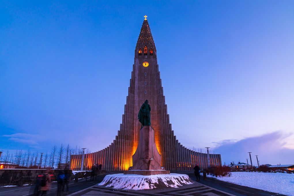 Hallgrimskirkja Lutheran church illuminated at dusk in Reykjavik, Iceland with dramatic blue sky and clouds.
