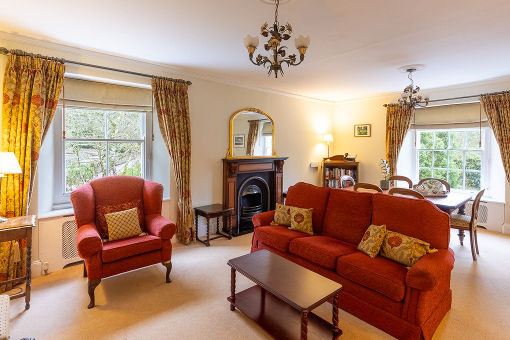 Bright living room with red sofas and large windows overlooking greenery in holiday apartment - interior photography