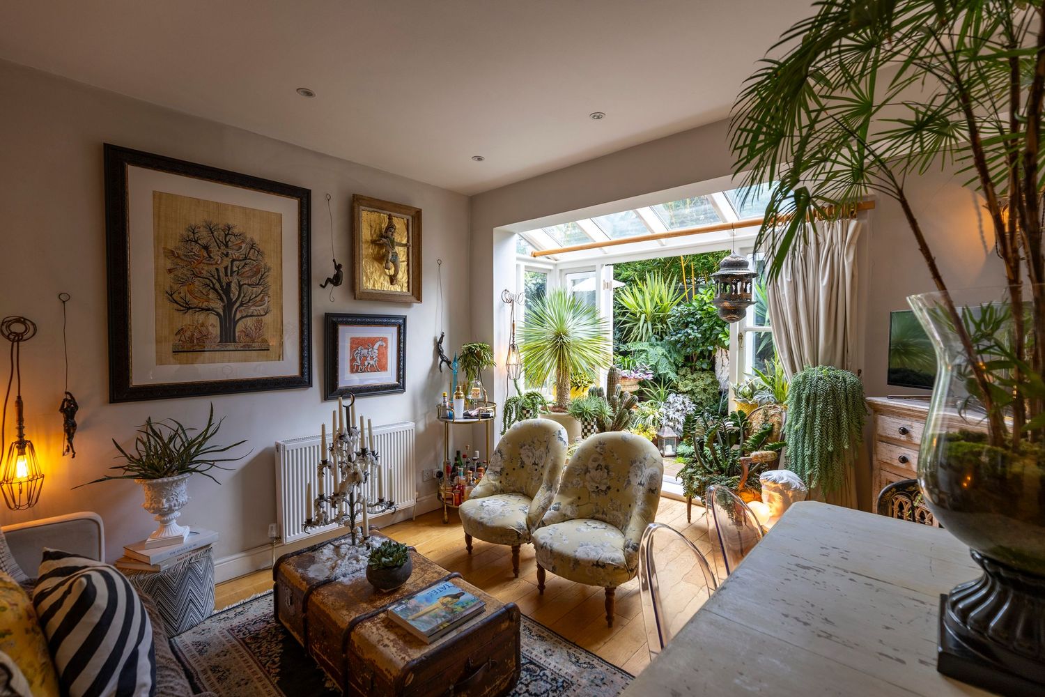 Bright bohemian living room with tropical plants, natural light and garden views for interior design photography.