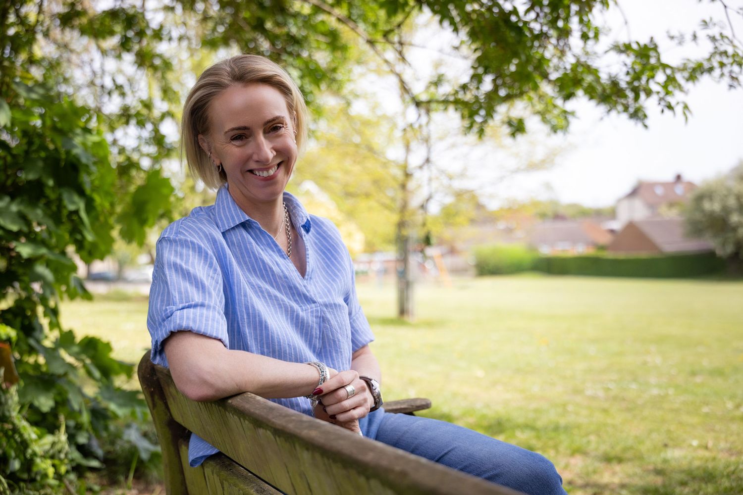 Professional personal branding portrait of a woman sitting on a bench in a garden setting.