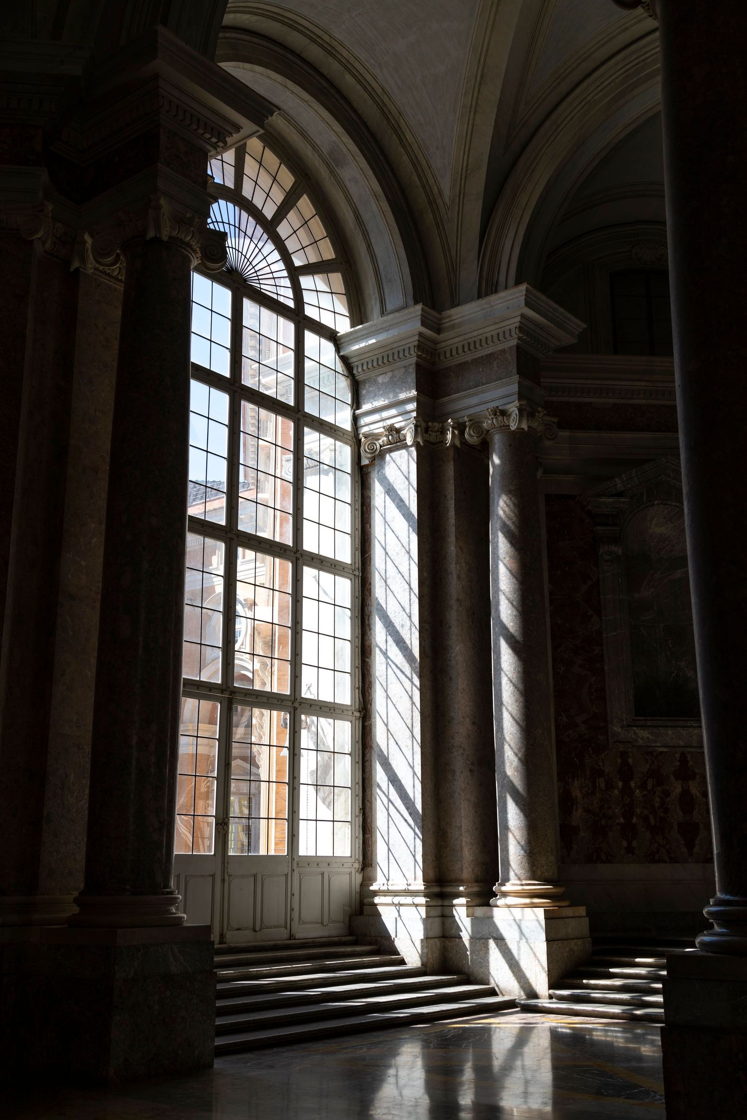 Architectural interior photography of grand Baroque hall with marble columns, arched windows and dramatic natural light.
