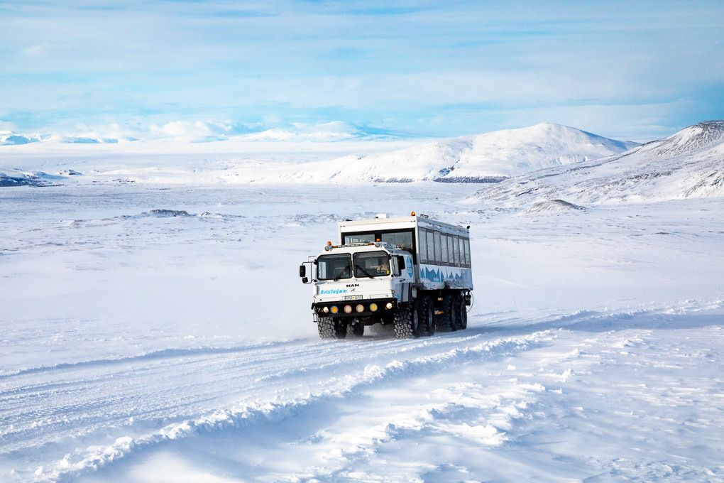 A convoy of trucks travels through a snowy winter landscape towards Into The Glacier in Iceland.