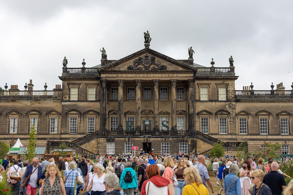 Crowd of tourists gathered outside the grand facade of Wentworth Woodhouse, a historic English mansion.