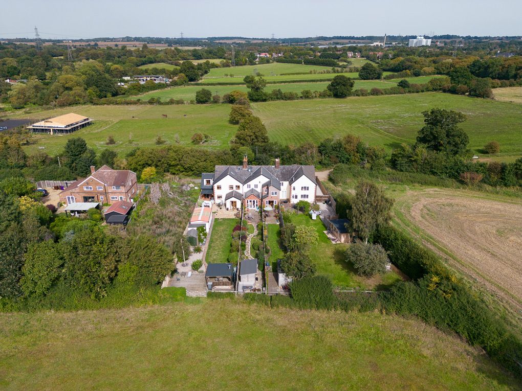 Aerial view of countryside homes nestled among green fields and trees seen from a sweeping panoramic perspective.