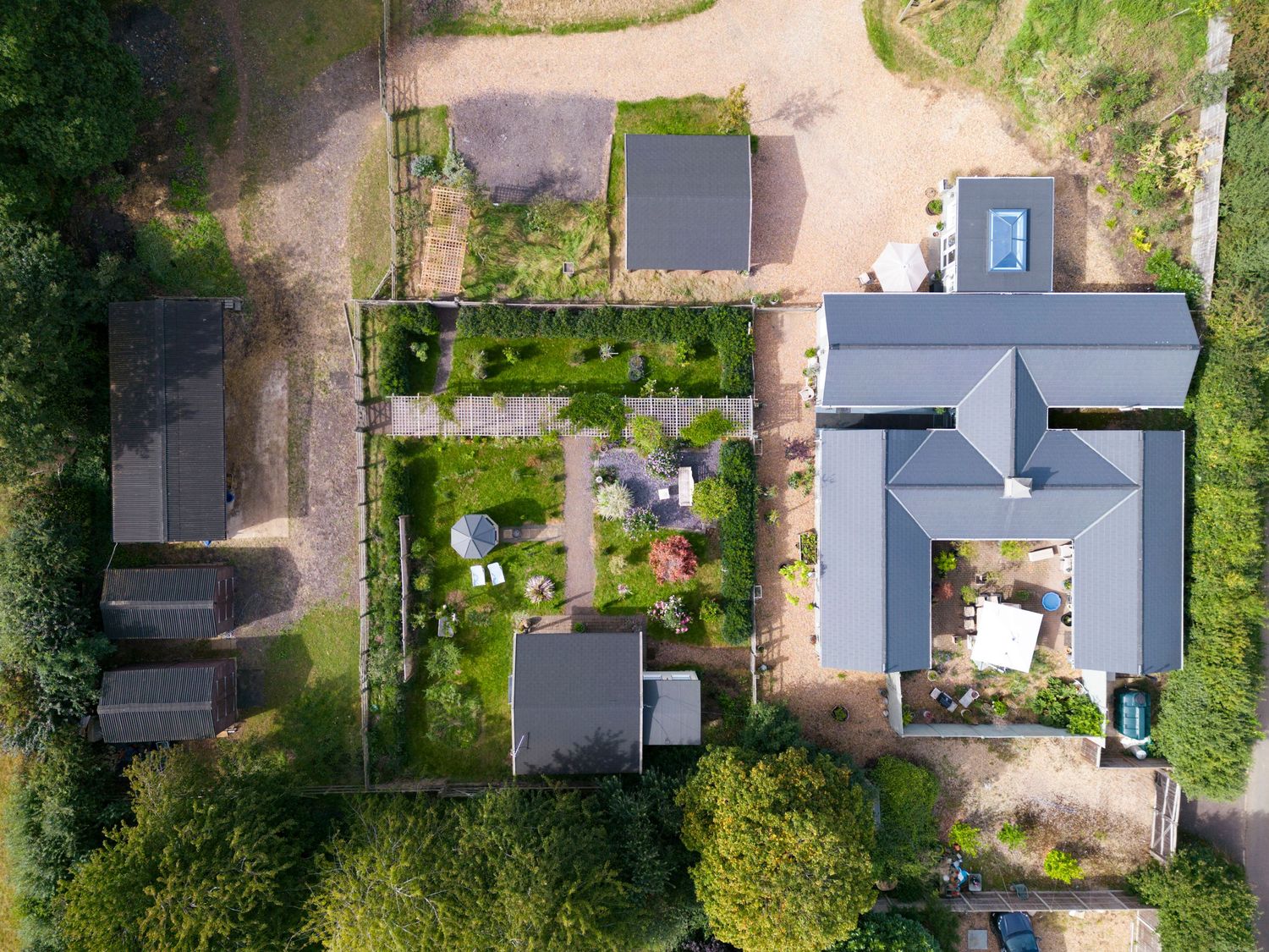 Bird’s-eye aerial view of countryside estate with landscaped grounds, woodland setting and luxury residential buildings.