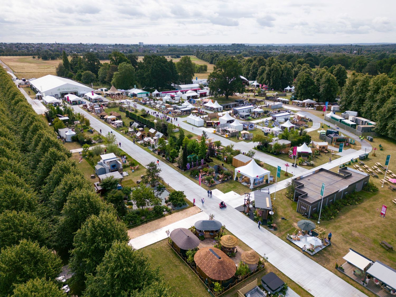 Aerial drone photograph of a large outdoor flower show featuring exhibition stands, display gardens, visitor areas and surrounding parkland.