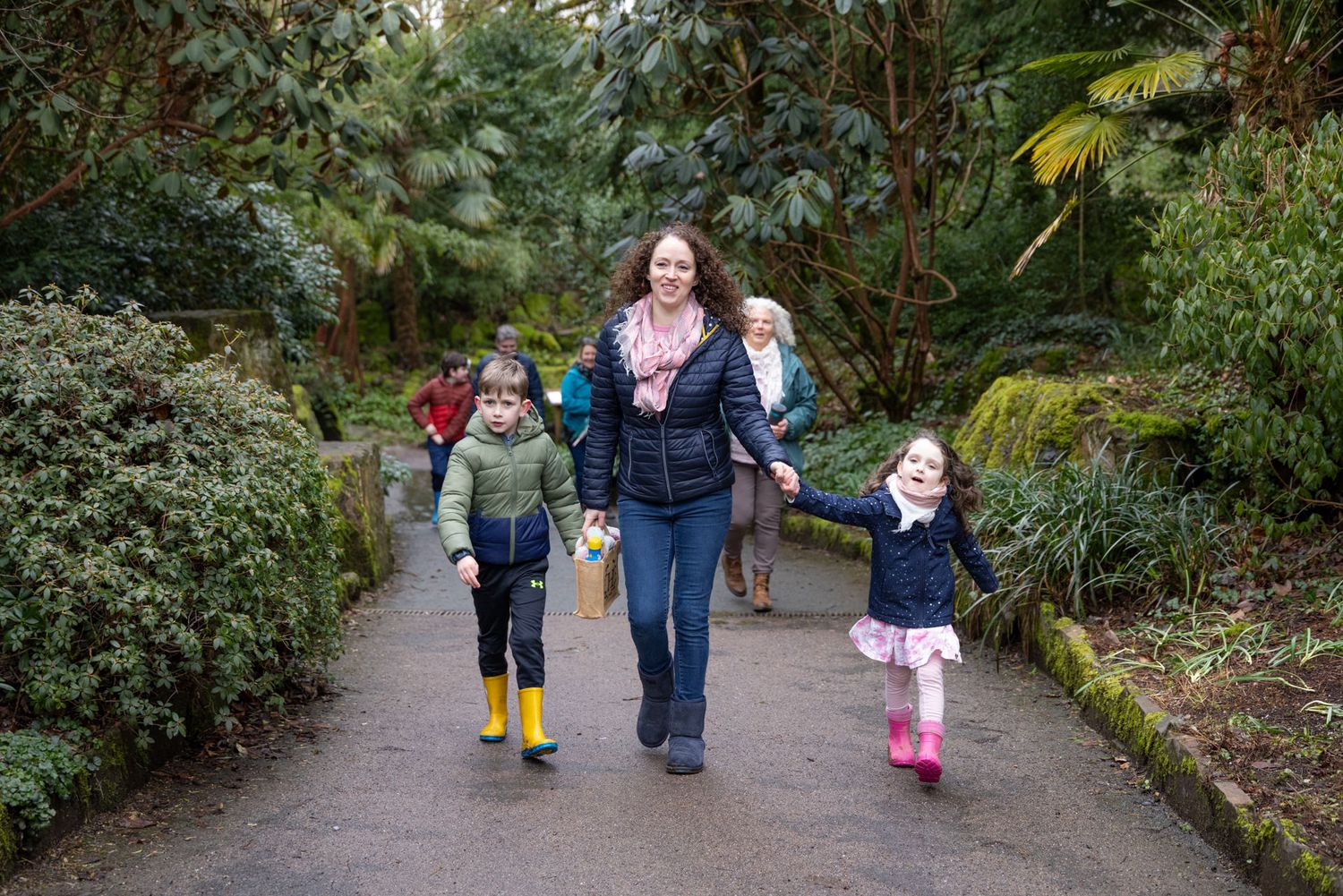 Child walking with parent along woodland path at RHS Rosemoor during the Wind in the Willows garden adventure trail