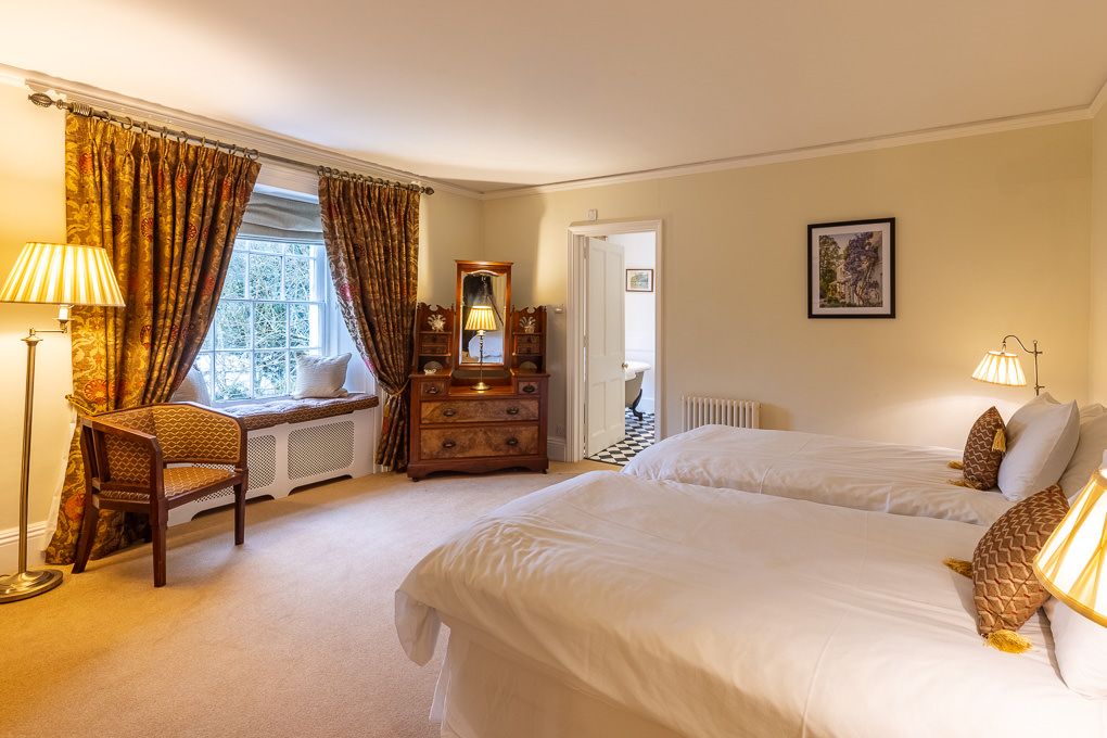 Elegant twin bedroom in holiday apartment with warm lighting, wooden furniture and soft furnishings - interior photography