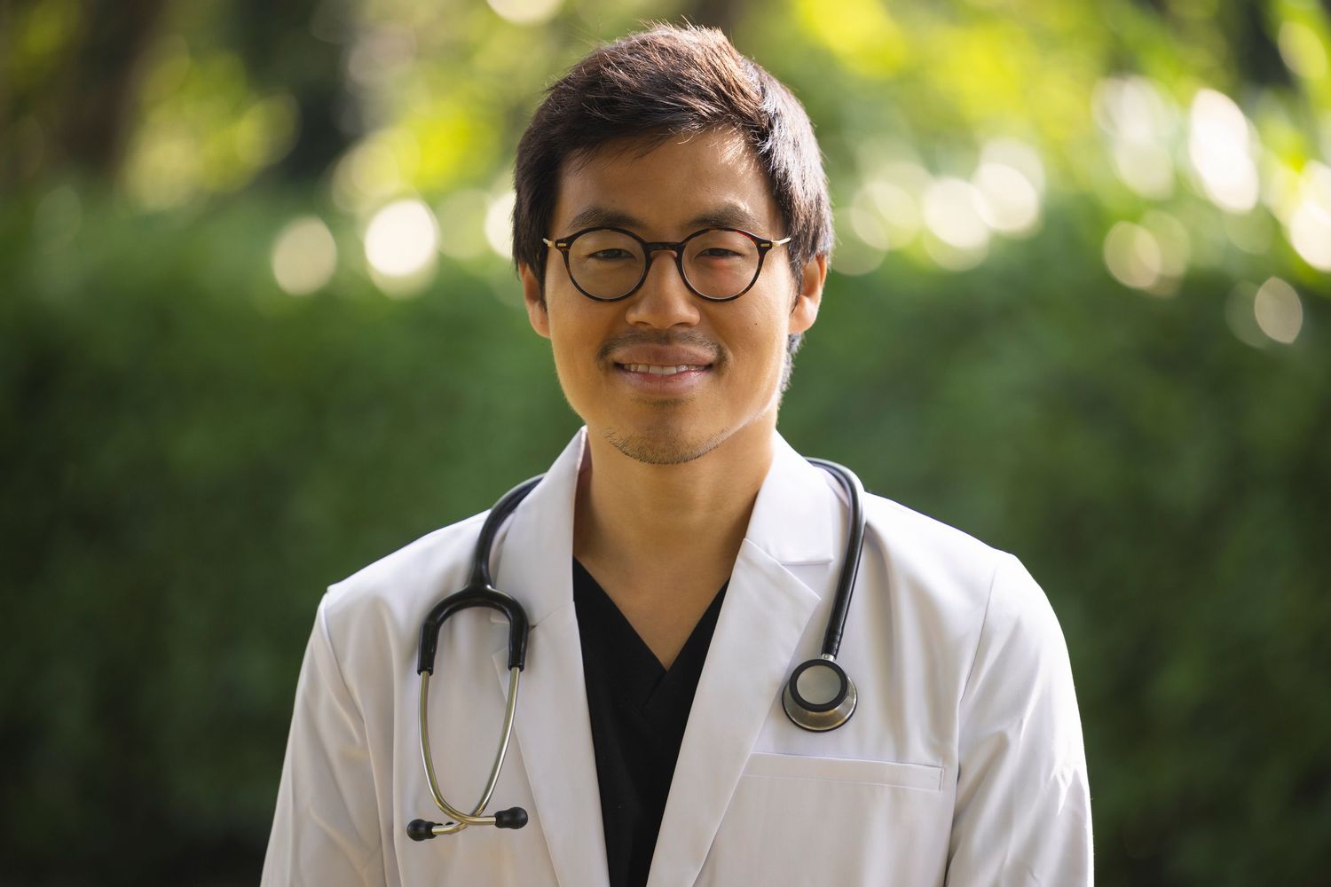 Professional portrait of doctor wearing a white coat and stethoscope outdoors, photographed for healthcare branding and medical marketing.