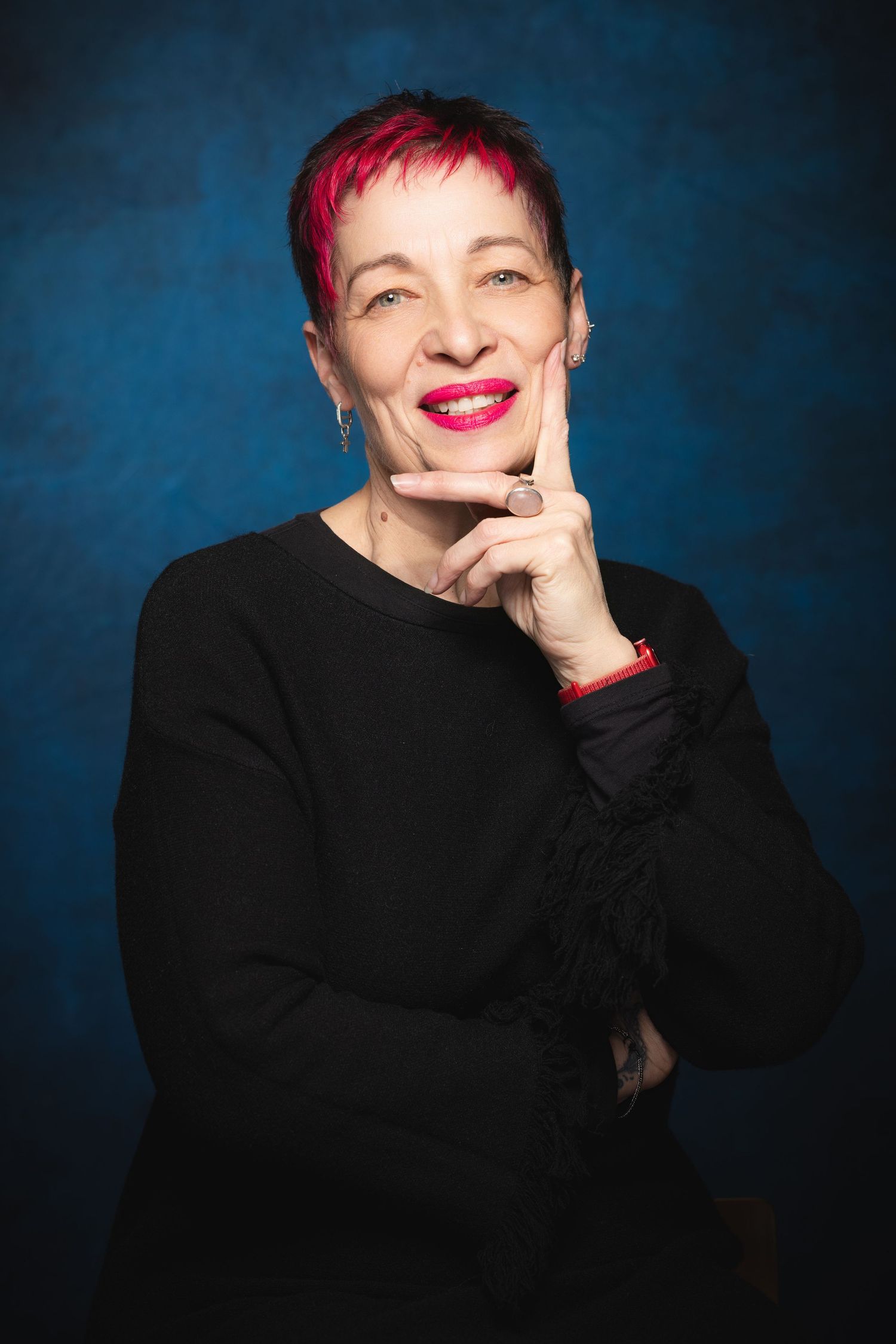 Actor headshot of performer with pink hair photographed against blue studio backdrop at Castle Theatre Wellingborough