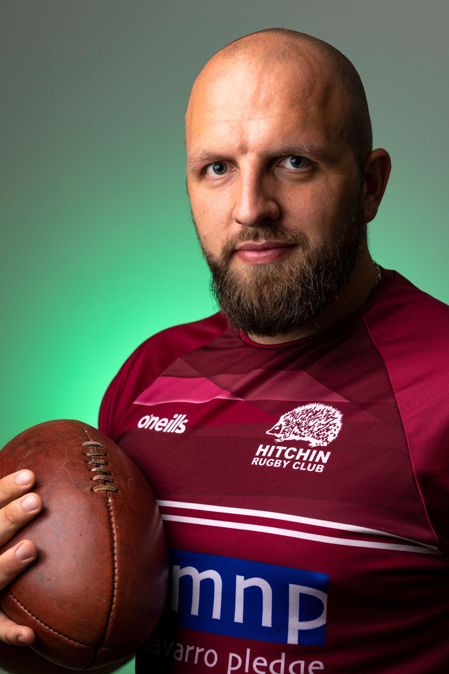 Professional rugby player portrait wearing Hitchin Rugby Club jersey and holding a rugby ball during a sports branding photography session.
