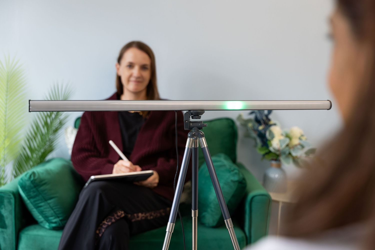 A therapist takes notes while sitting across from a patient during a counseling session in a modern office.