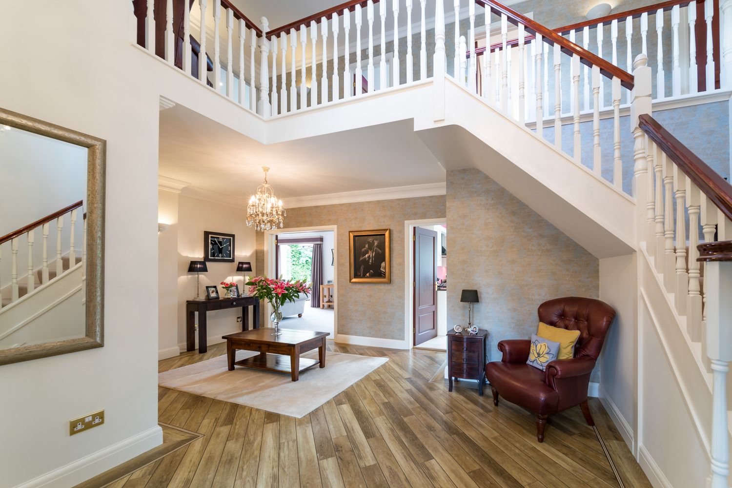 Property photo of a white interior staircase with wood handrails leads up to a bright landing with hardwood floors and home furnishings.