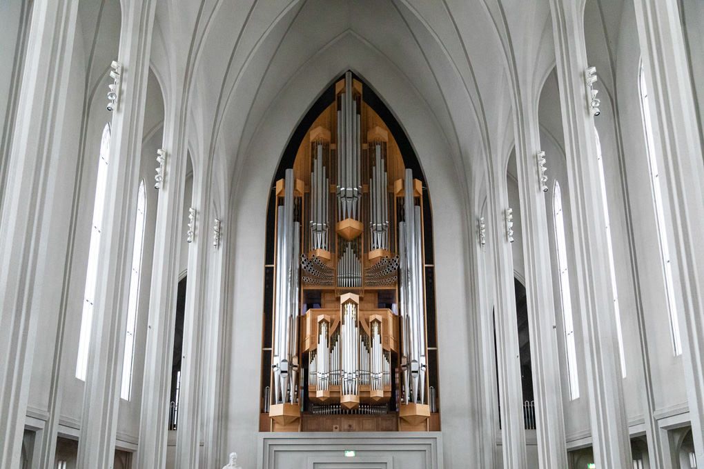 Interior view of Hallgrímskirkja, Reykjavík’s Iconic Church with soaring white arched vaults and a majestic pipe organ at the far end.