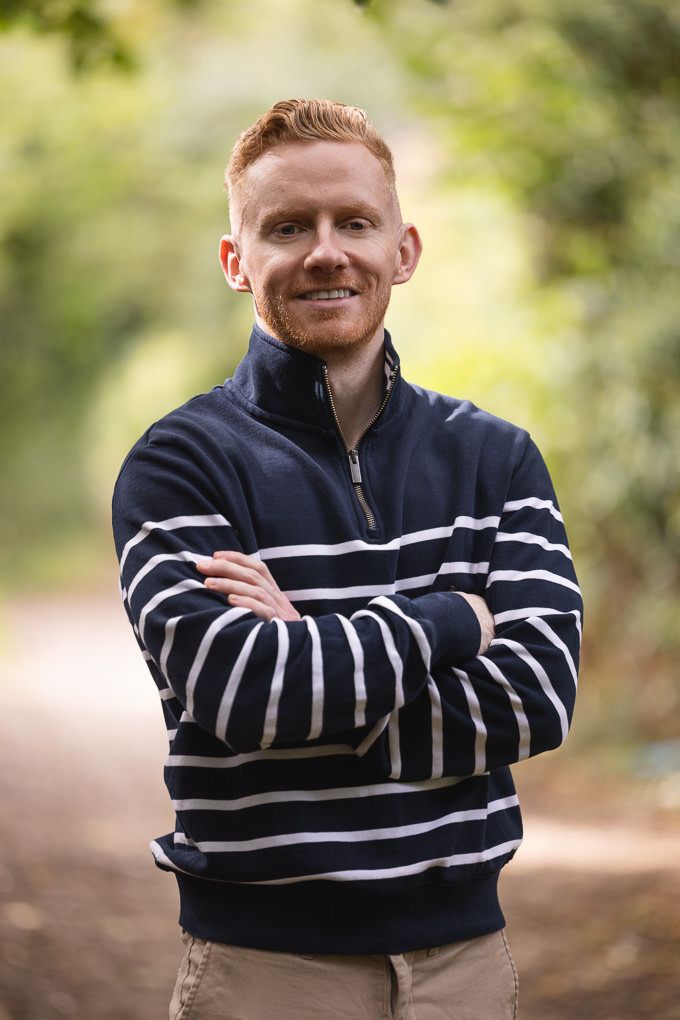 Person posing outdoors wearing a navy and white striped sweater against a natural blurred background.