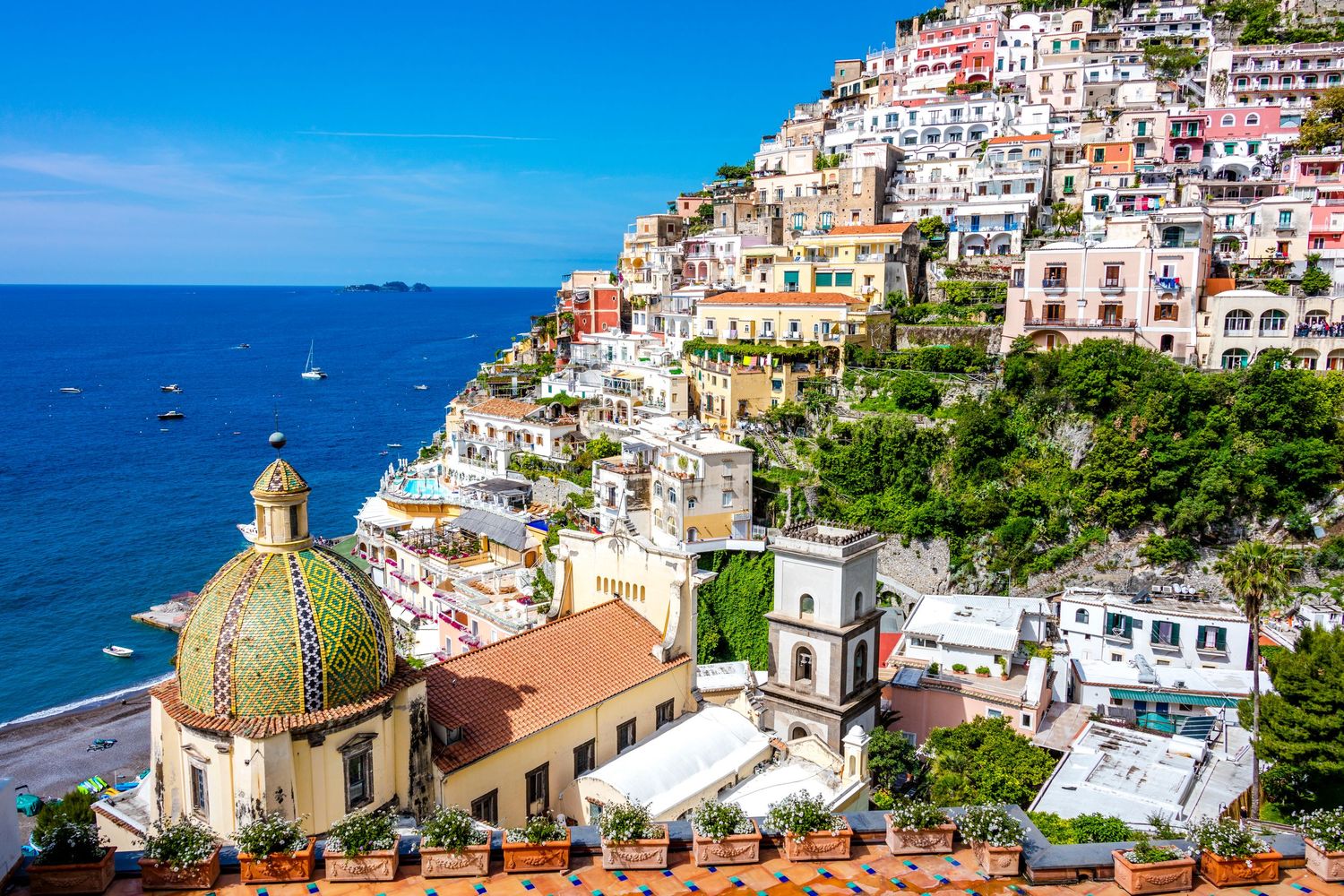 Colorful buildings cascade down a steep hillside overlooking the blue Mediterranean Sea in Positano, Italy.