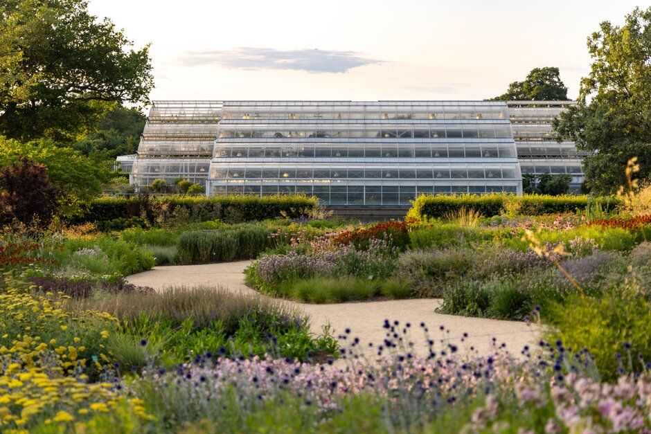 Greenhouse buildings and native wildflower gardens blend harmoniously into the natural landscape on a sunny day.