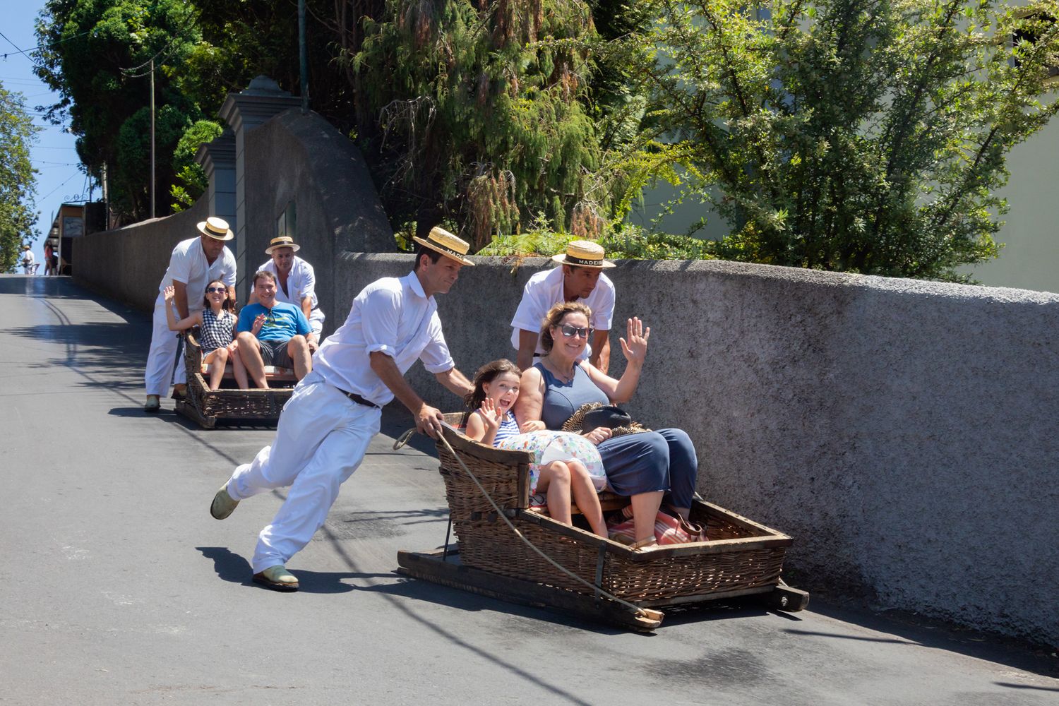 People enjoying a traditional toboggan ride down a steep street on a sunny day.