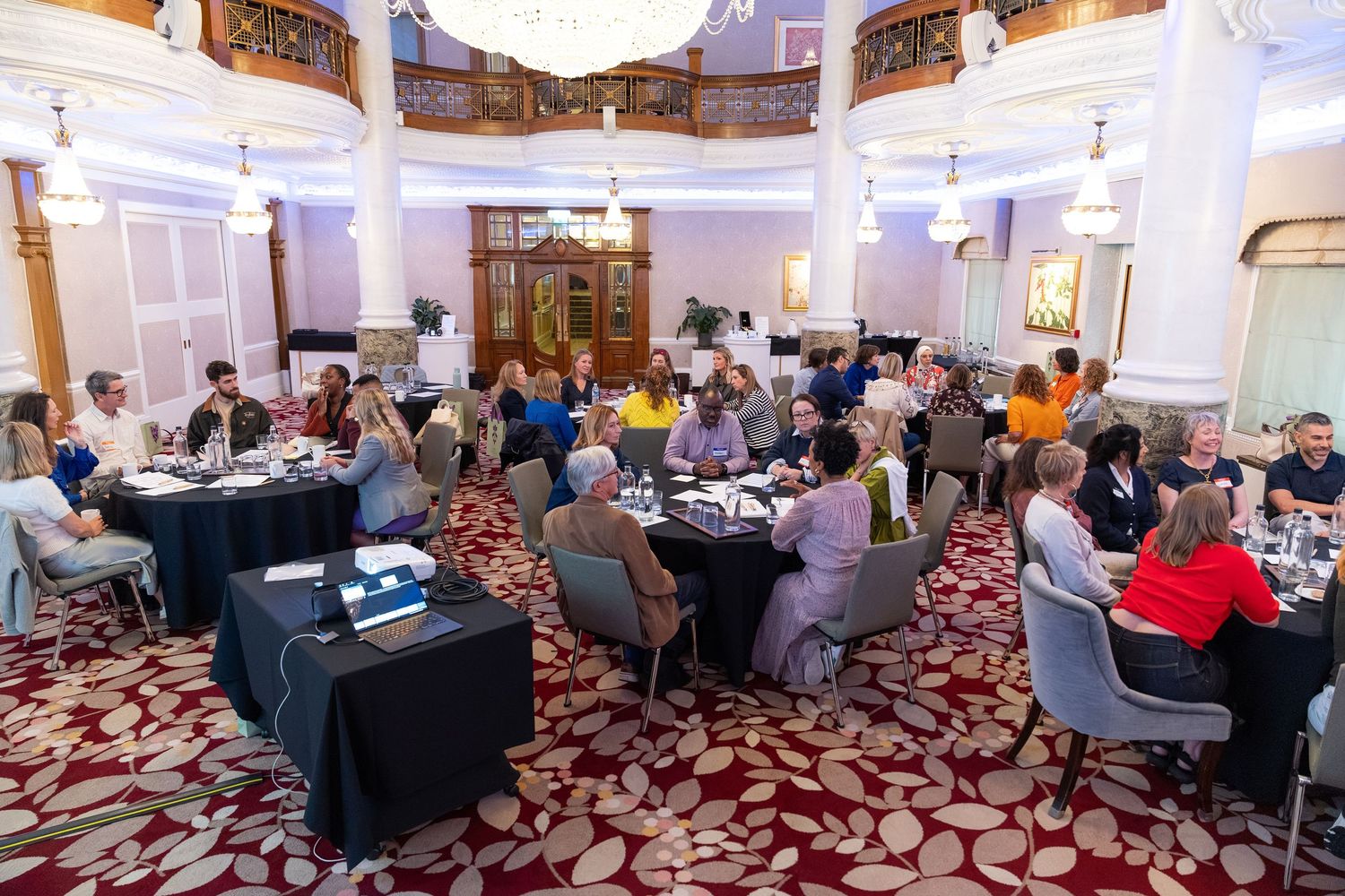 Elegant banquet hall with guests seated at round tables during a formal meeting or conference event.