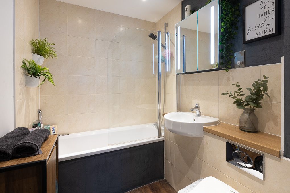 Property photography of a modern bathroom interior with a wooden vanity, a vessel sink, and a sleek black accent concrete wall.