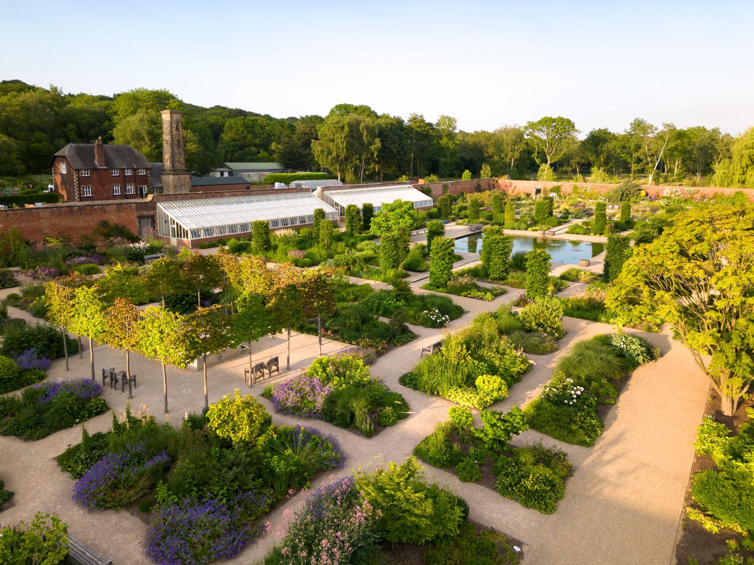 Aerial drone photograph of a formal walled garden featuring geometric planting beds, gravel pathways and historic garden buildings.