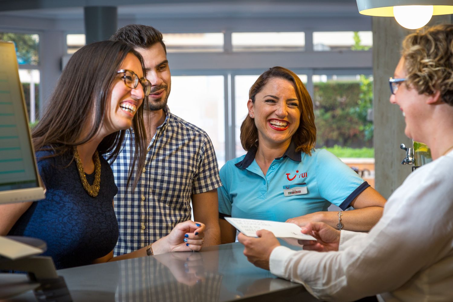 A TUI rep in uniform talking to guests in a hotel lobby.
