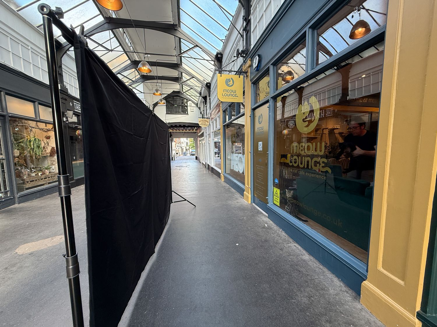 Modern glass-roofed shopping arcade interior with historic architecture and rows of store facades.