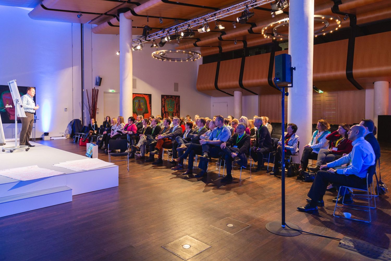 Speaker presenting to delegates during a business conference in a modern event venue with audience engagement