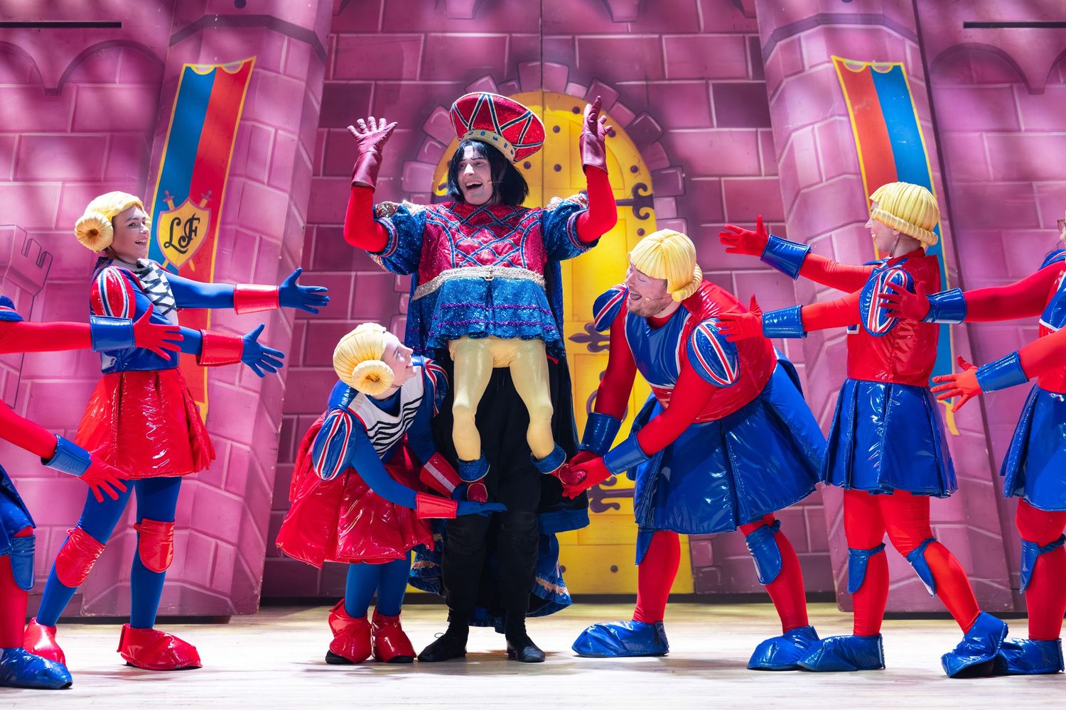Costumed actors perform on a vibrant pink castle stage set during Shrek The Musical at Castle Theatre, Wellingborough