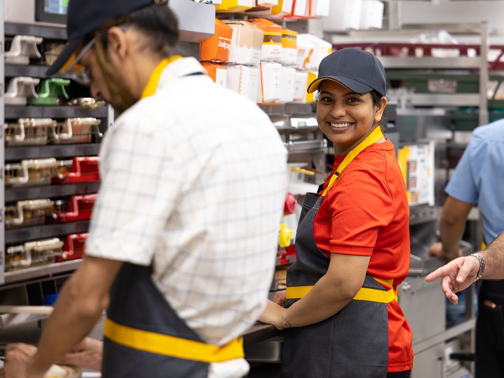 Smiling McDonald’s kitchen employee during the Rickmansworth restaurant opening, photographed for PR and press use, showing team engagement.
