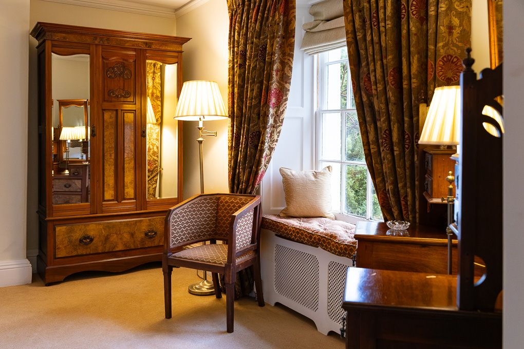 Traditional interior with antique wooden furniture, window seat and floral curtains in holiday apartment - interior photography