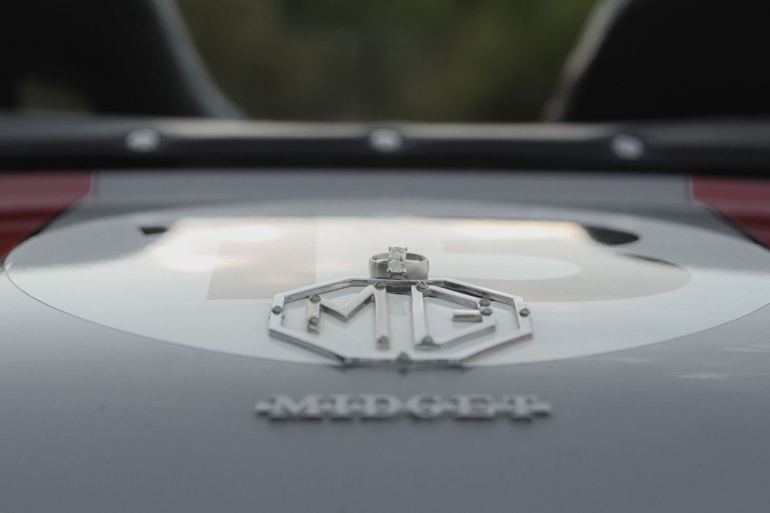 Close-up of silver MG car hood ornament and badge on luxury vehicle exterior.