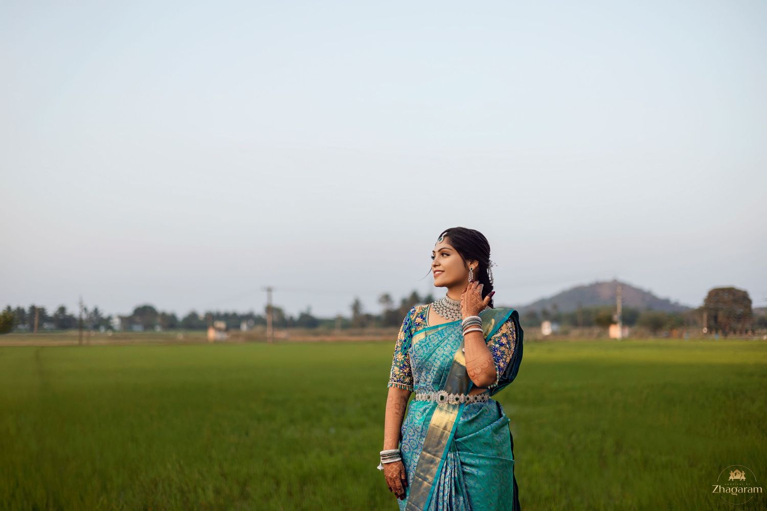 Bride in blue saree posing in paddy field during golden hour pre-wedding photography Tamil Nadu
