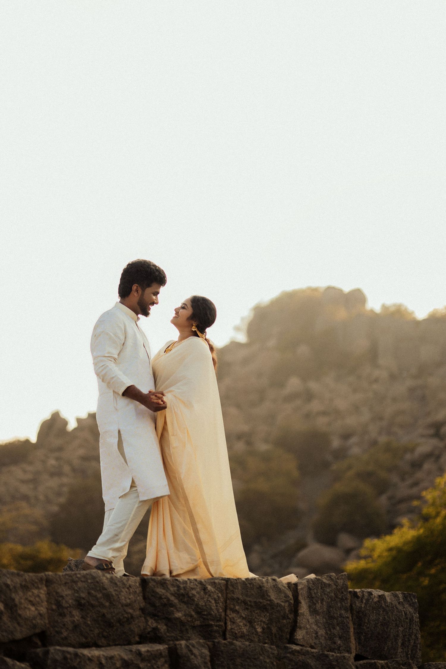 Couple in white traditional attire romantic pre-wedding shoot on hilltop at sunset Tamil Nadu