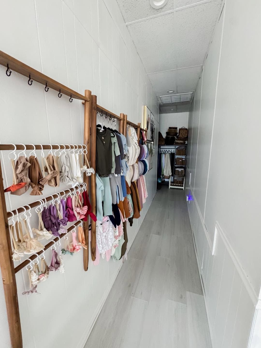Narrow walk-in closet with wooden ladder racks displaying organized children's clothing along white walls.