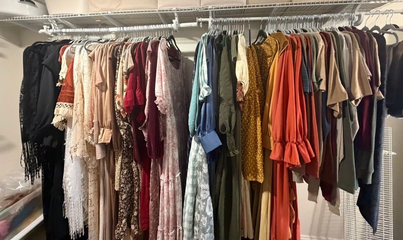 A wardrobe rack filled with colorful client dresses in various styles for a photography studio.