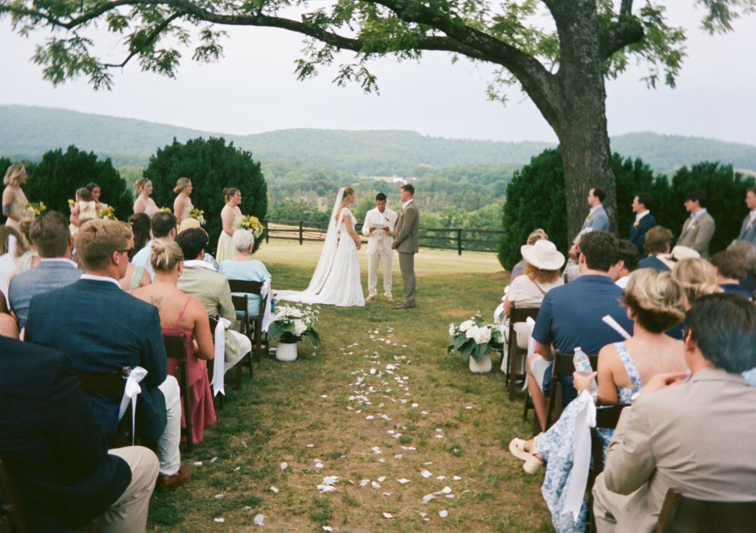 Outdoor wedding ceremony with guests seated on lawn with mountain views.