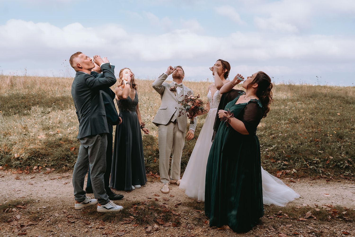 Braut & Gästegruppe stoßen auf Feldweg an – Hochzeitsfotograf Schweiz Ubomigraphy.