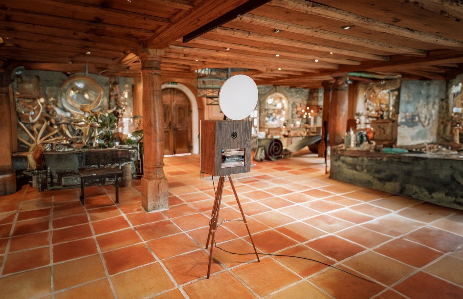 Mobile Fotobox steht einsatzbereit im rustikalen Holzsaal. Fotobox mieten für unvergessliche Events und Hochzeiten Schweiz.
