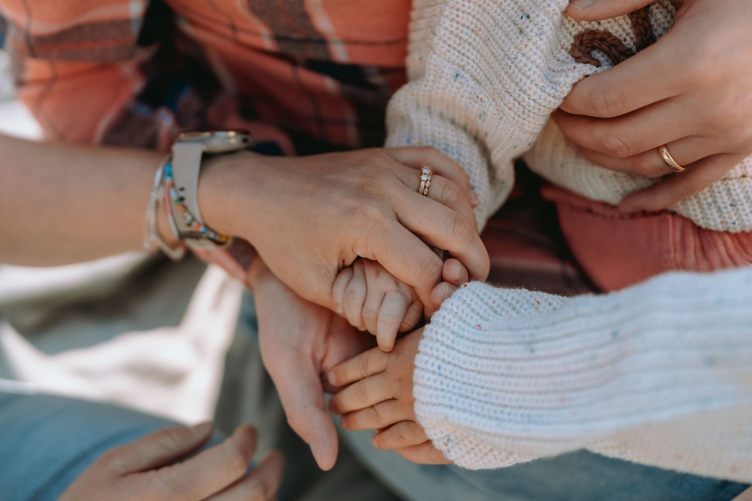 Familienhände und kleine Babyhände liegen liebevoll übereinander. Authentische Newborn- und Familienfotografie in Solothurn.