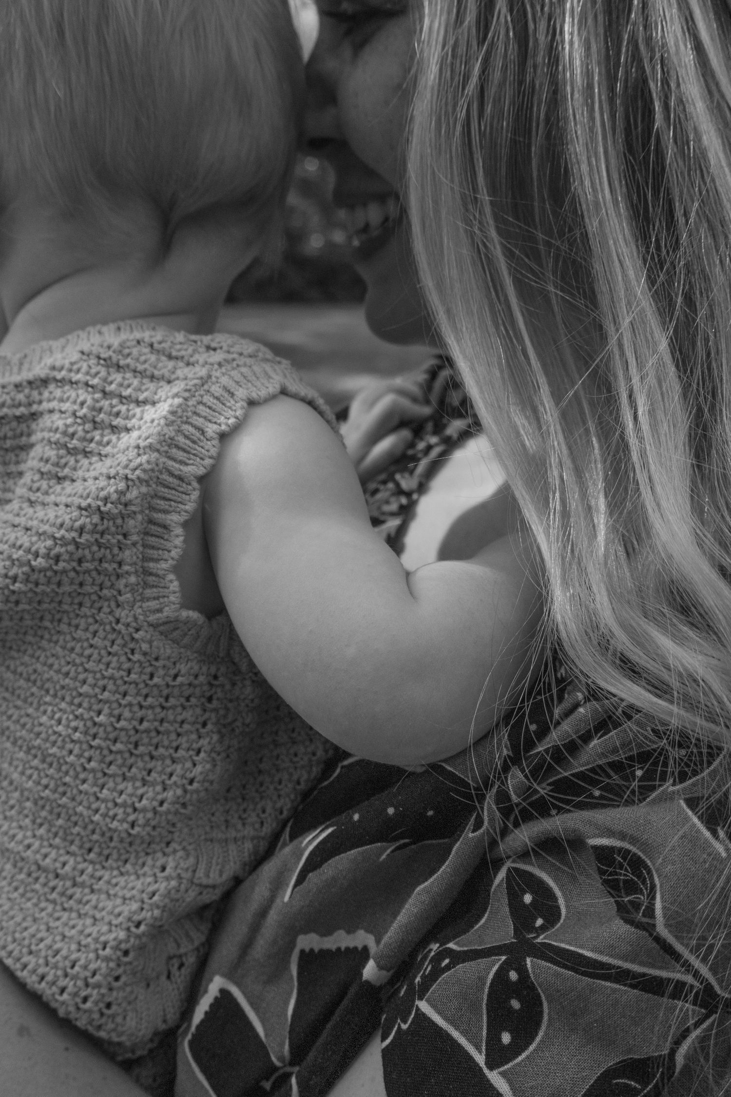 Black and white photo of a mother kissing her baby tenderly while holding the child close.