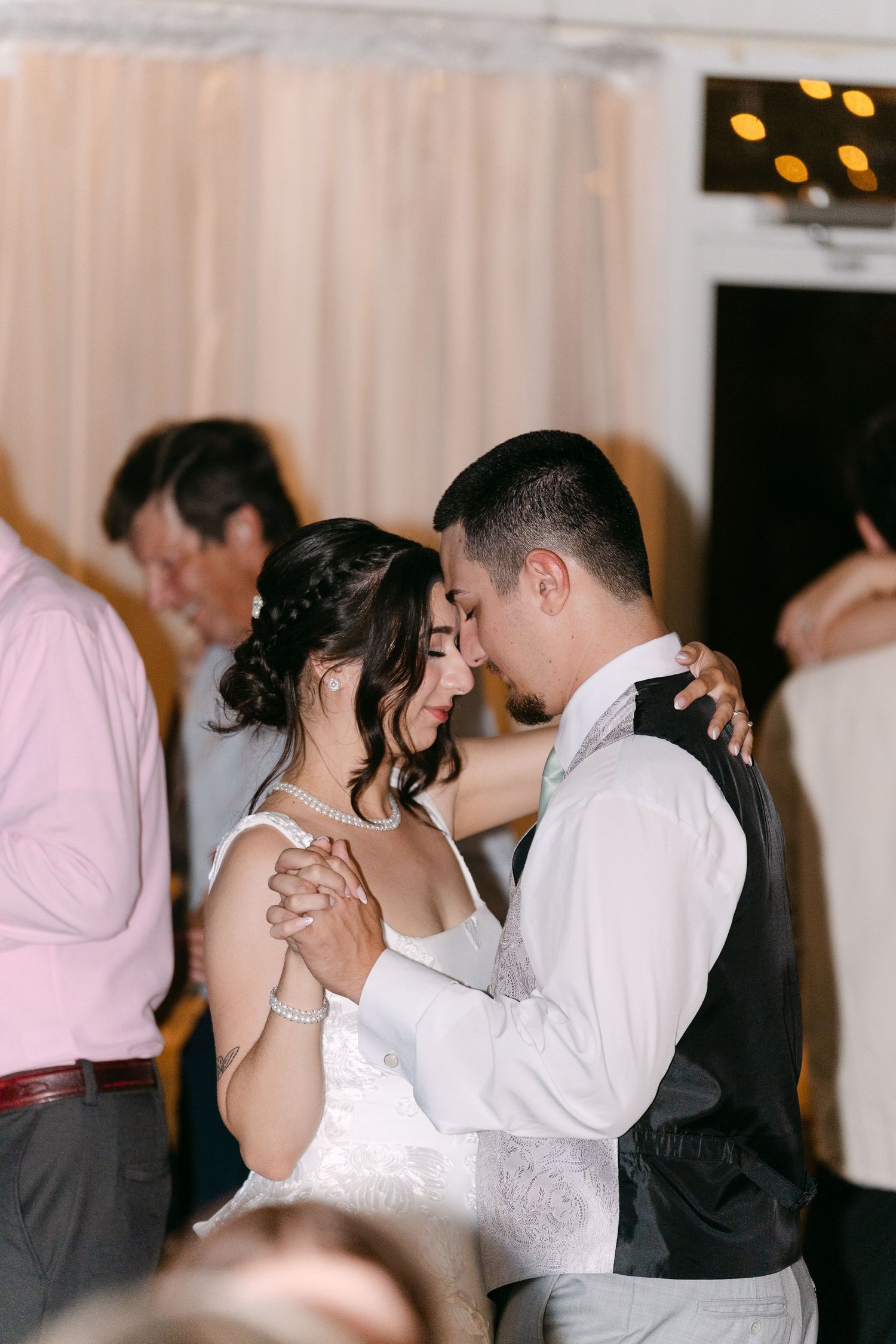 Bride and groom share intimate first dance at wedding reception, surrounded by guests in elegant venue.