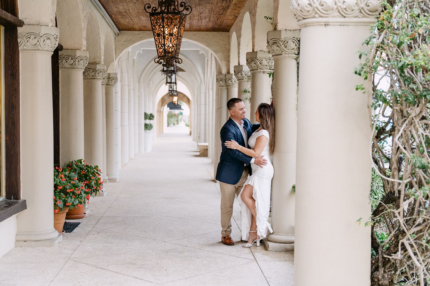Couple dancing and laughing together in a beautiful white stone colonnade with ornate hanging lanterns.